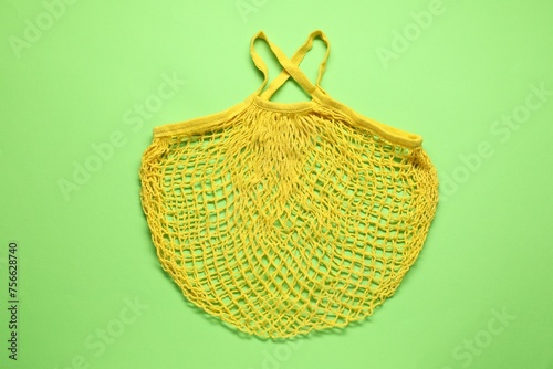 Yellow net bag on green background, top view