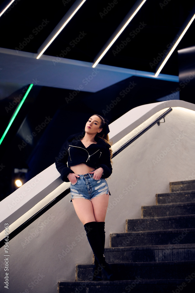 Obraz premium Beautiful girl blonde in denim shorts and a black jacket posing on the street