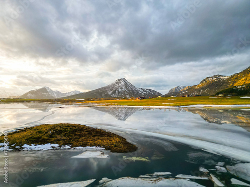 Reflective waters and rugged peaks create a dramatic natural scene in this mountainous winter terrain.