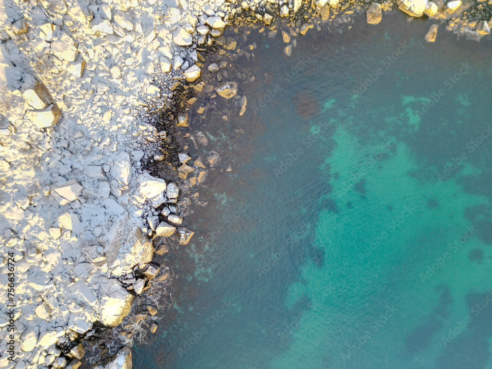 Above the frozen chaos where ice chunks scatter along the snowy coastline. Above the frozen chaos where ice chunks scatter along the snowy coastline.