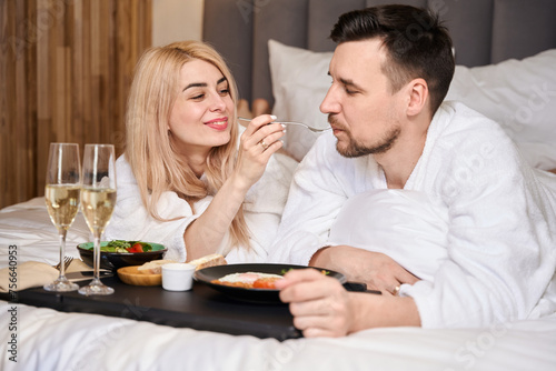 Young married couple enjoying breakfast in bed