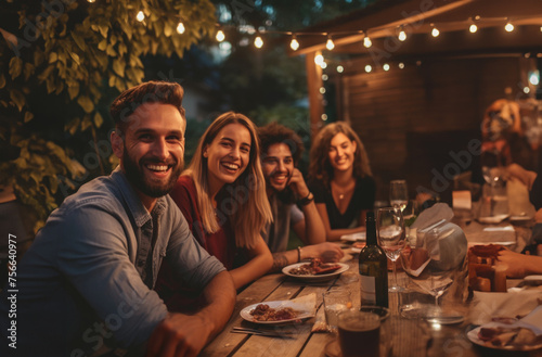 Young people dining and having fun drinking red wine together outdoor at  dinner party