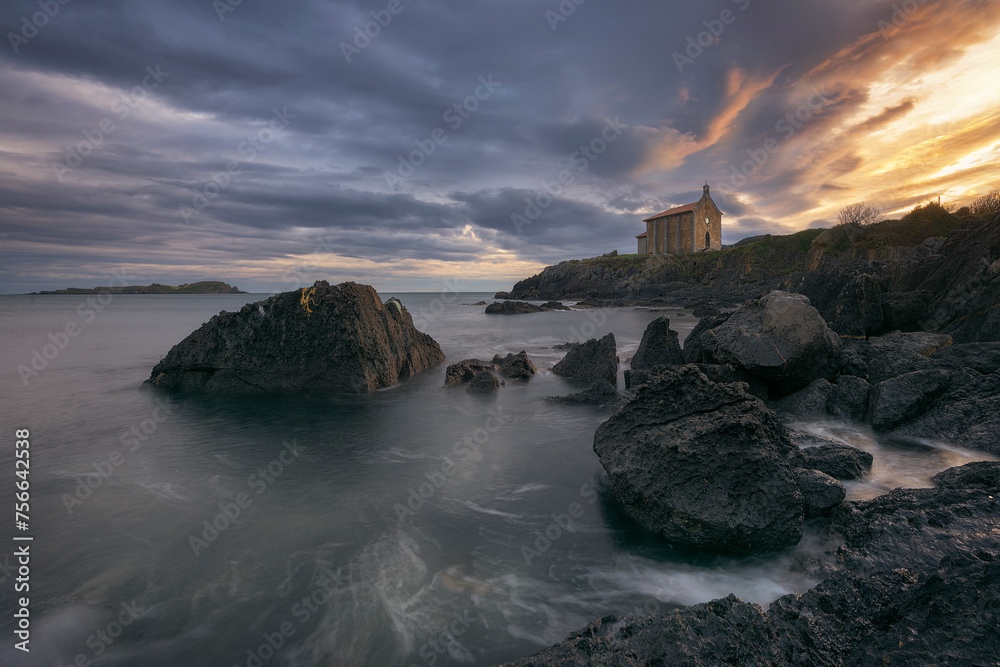 Sunrise at the hermitage of Santa Katalina, Mundaka, with the sea and rocks in the foreground and a dramatic sky