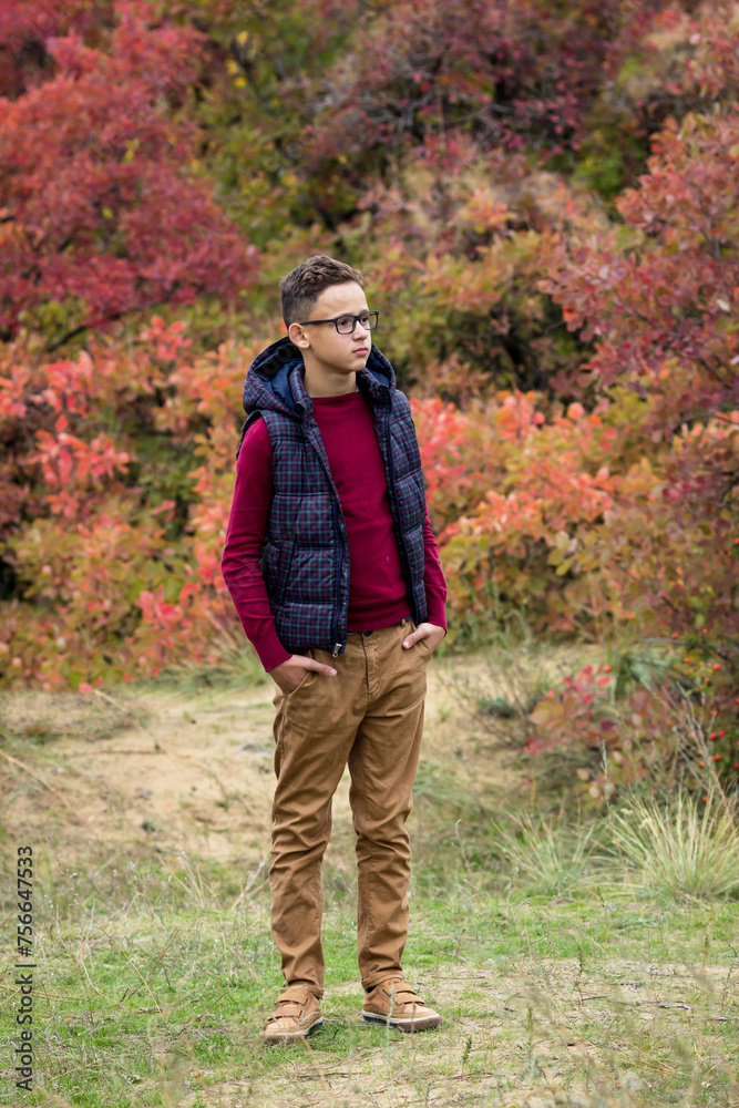 Teenage boy in the autumn forest looks into the distance