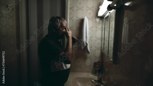 One elderly man in front of bathroom mirror feeling STRESS and overwhelmed by problems during challenging years, depicting old age photo