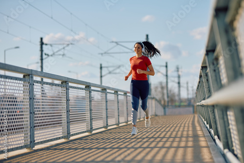 Young happy sportswoman jogging outdoors. © Drazen