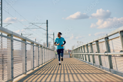 Black male athlete running over the bridge during outdoor sports training.