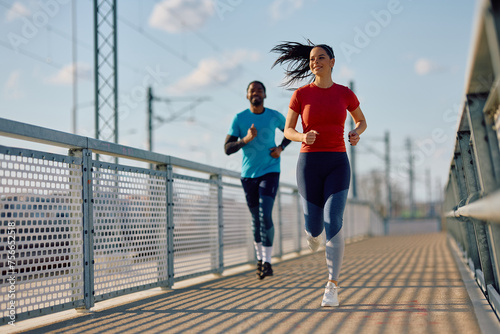 Athletic couple jogging while having sports training outdoors.