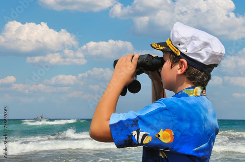 Boy with binocularsA boy with binoculars watches a military boat