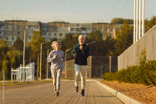 Active senior pair enjoy running, sporty physically energetic older man and woman outdoor jogging. Elderly people on street physical exercise, open air activity to boost mood, energy levels, memory photo