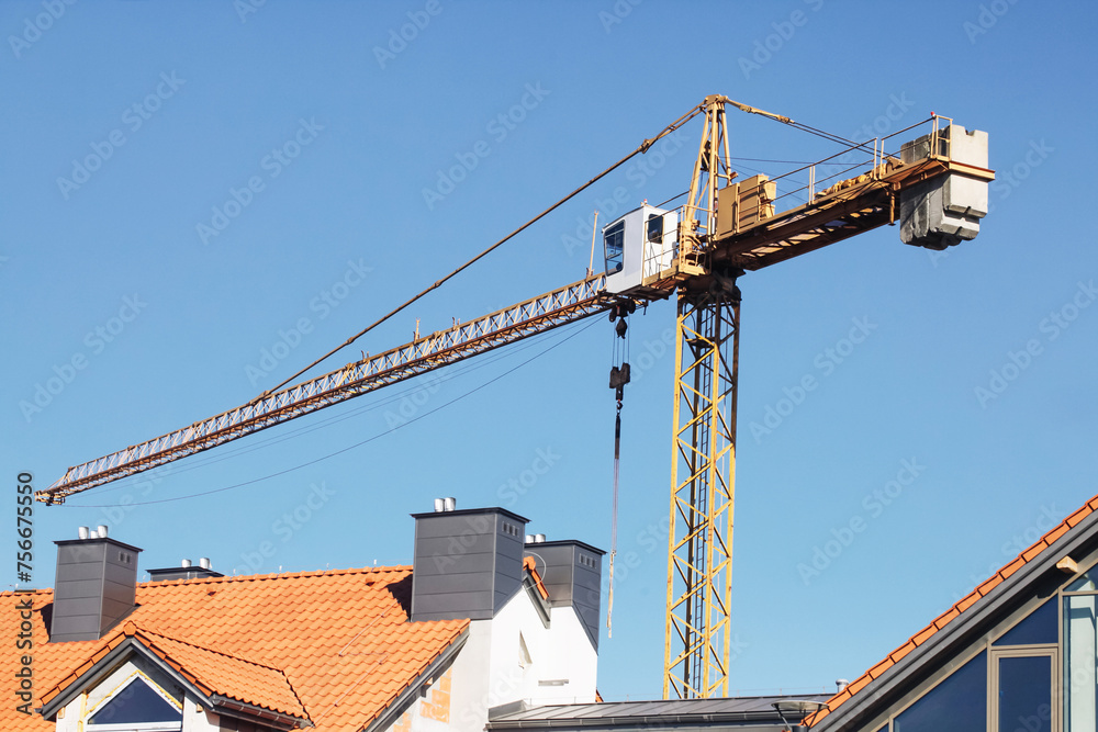 Crane background. Yellow paint heavy machinery equipment isolated on blue sky. Construction site view. Industrial building process. Block of flats in progress. Process of building.