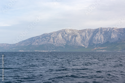 Scenic view of Makarska Riviera with untamed mountain range Biokovo in Dinaric Alps. Majestic coastline of Adriatic Mediterranean Sea in Dalmatia, South Croatia, Europe. Boat tour in Balkan peninsula