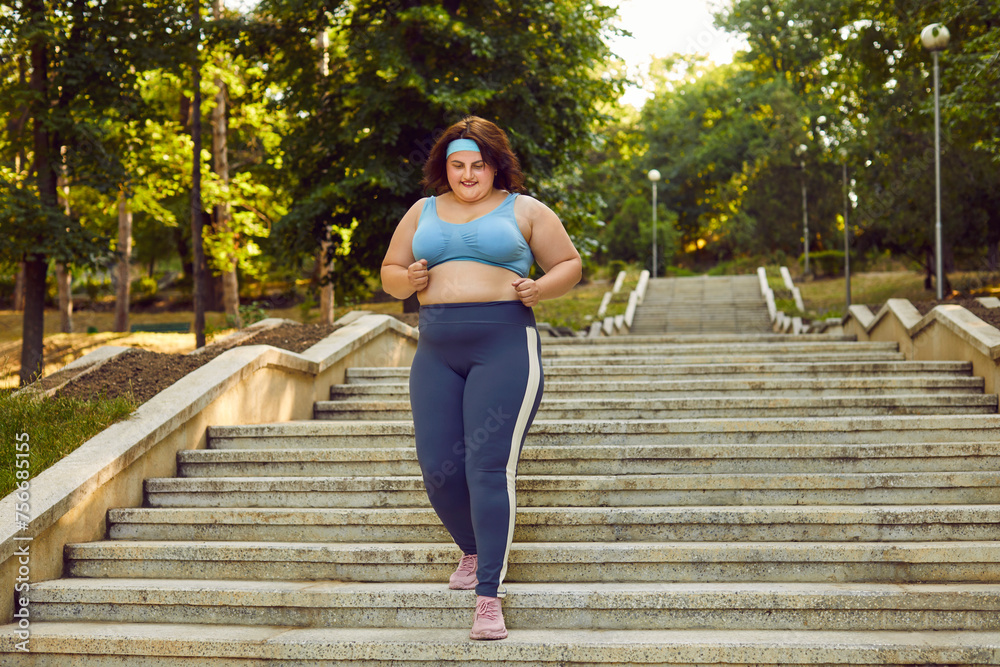 Overweight happy smiling fat woman having sport training in the summer city park running outdoors. Plus size girl wearing sportswear jogging in nature. Weight loss, sport lifestyle concept. Overweight happy smiling fat woman having sport training in the summer city park running outdoors. Plus size girl wearing sportswear jogging in nature. Weight loss, sport lifestyle concept.
