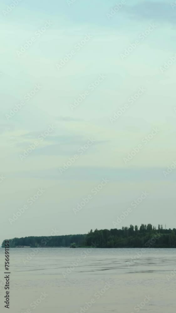 Vertical video. Large river with white clouds and green forest on horizon. Beautiful nature view of river summer windy cloudy day, slow motion Vertical video. Large river with white clouds and green forest on horizon. Beautiful nature view of river summer windy cloudy day, slow motion