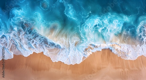 Aerial top view capturing the mesmerizing contrast of sea waves crashing onto a sandy beach, showcasing nature's beautiful palette of blue and brown.