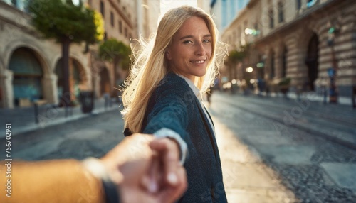  Young woman leading man through city street by hand photo