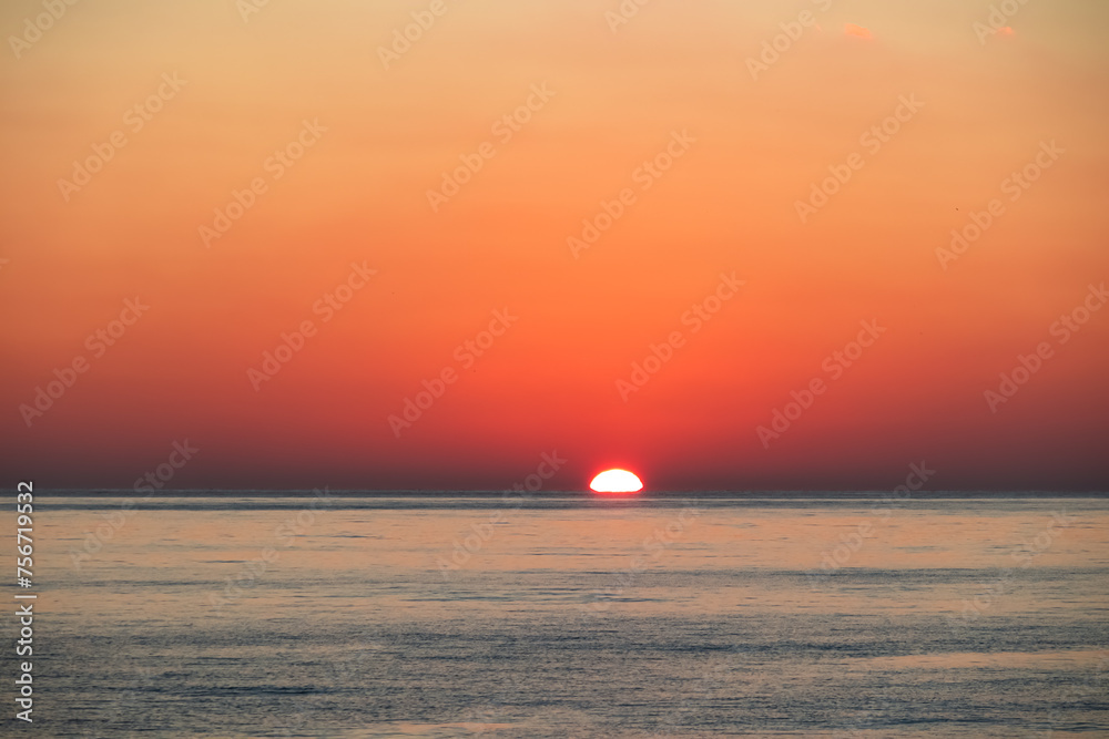 Watching dramatic sunset at coastal village Funtana, Istria, Croatia, EU. Calm sea surface reflects vibrant colors of sky. Vacation at Adriatic Mediterranean Sea. Romantic specular reflection. Sparkle
