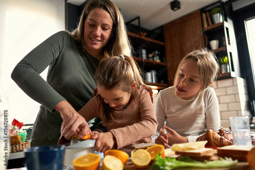 Laughter echoes in the kitchen as mother and daughters squeeze oranges, creating a refreshing touch to their delightful breakfast. Laughter echoes in the kitchen as mother and daughters squeeze oranges, creating a refreshing touch to their delightful breakfast.