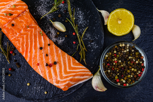 Raw fillet of salmon fish and spices on a slate board