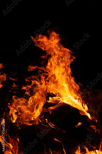 A mesmerizing close up of  bonfire in nature  with flames dancing against black background. heat and flickering flames create  captivating event  reminiscent of  cozy fireplace or campfire
