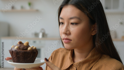 Asian korean woman hungry girl in kitchen hold high-calorie cake deny to eat chocolate dessert keep diet weight refusing flour gluten sweet food no sugar addiction stop overeating avoid unhealthy eat