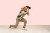 Male photographer with modern camera on pink background