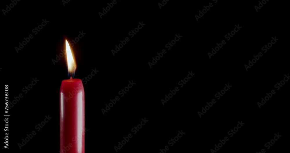 A single red candle burning. Isolated candle burning with dark background. Red paraffin candle with yellow shades burns on a black background. Background or illustration of remembrance or celebration. A single red candle burning. Isolated candle burning with dark background. Red paraffin candle with yellow shades burns on a black background. Background or illustration of remembrance or celebration.