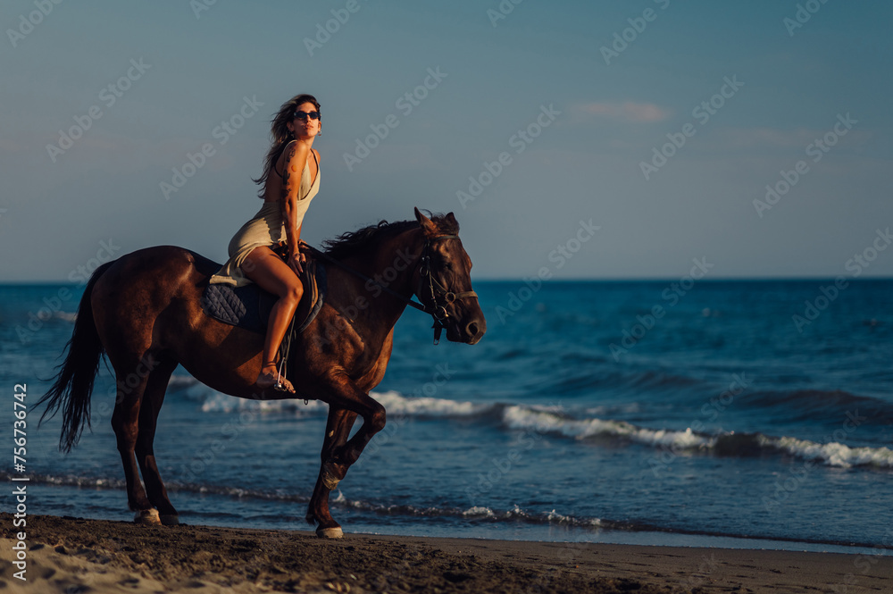 An attractive lady is horseback riding at summertime at the beach. An attractive lady is horseback riding at summertime at the beach.