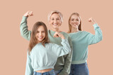 Little girl with her mom and grandmother showing muscles on beige background