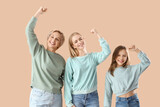 Happy little girl with her mom and grandmother on beige background