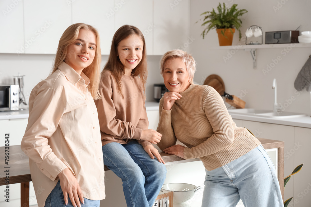 Little girl with her mom and grandmother smiling in kitchen Little girl with her mom and grandmother smiling in kitchen