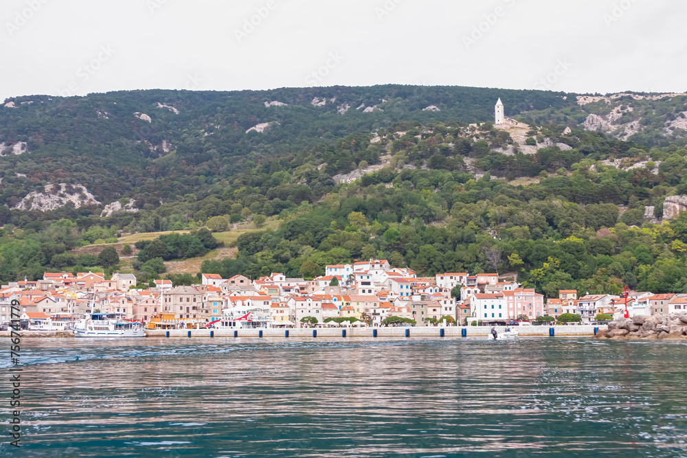 Scenic view of idyllic coastal town Baska, Krk Island, Primorje-Gorski Kotar, Croatia, Europe. Majestic coastline with high mountains and steep cliffs. Mediterranean Adriatic architecture of old town