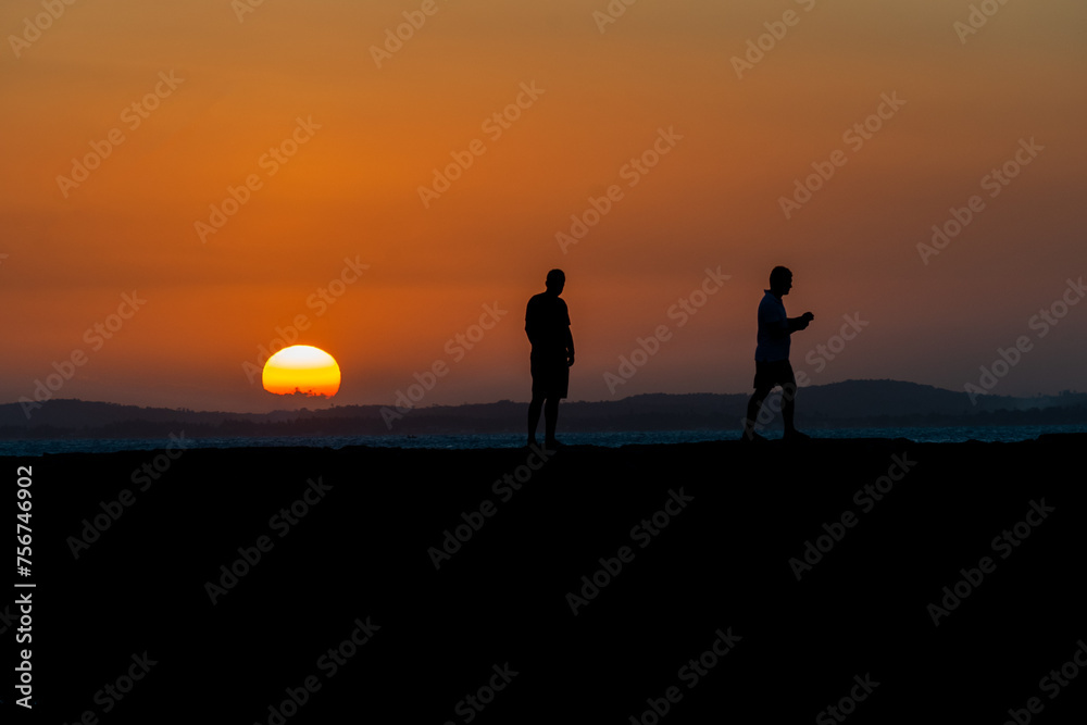 Two people, in silhouette, are seen on the Porto da Barra pier against the sunset in the city of Salvador, Bahia.