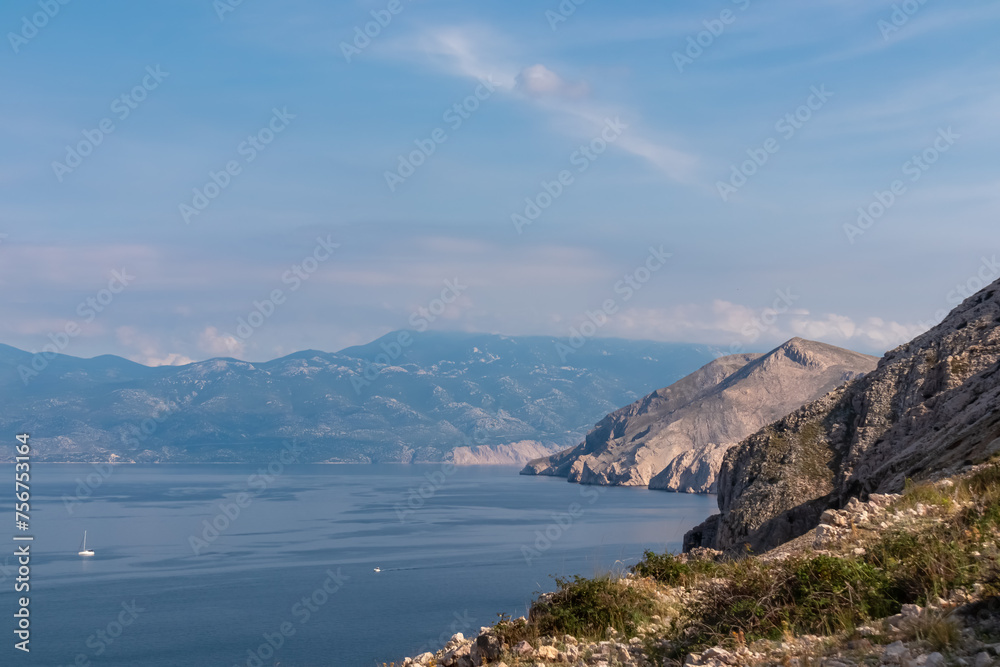 Coastal hiking trail along cliffs with scenic view of deserted island Prvic near tourist town Baska, Krk Otok, Primorje-Gorski Kotar, Croatia, Europe. Majestic coastline of Mediterranean Adriatic Sea