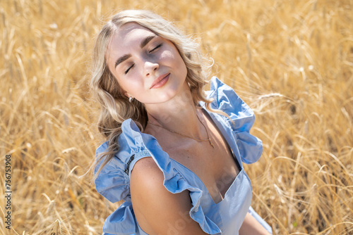 Young beautiful blonde girl posing in a wheat field