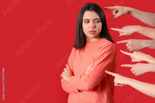 People pointing at young woman on red background. Accusation concept