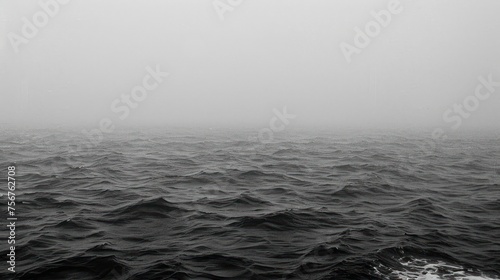 a black and white photo of a large body of water with a boat in the distance on a foggy day.