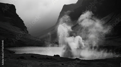 a black and white photo of a geyser spewing water into a body of water with mountains in the background.