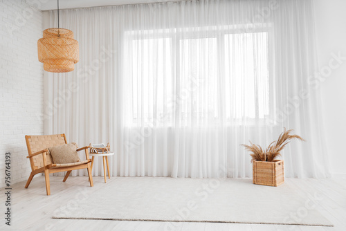 Lamp, carpet, pampas grass, chair and coffee table near light curtain in living room