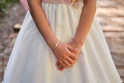 Detalle de las manos y pulsera de una niña vestida de comunión