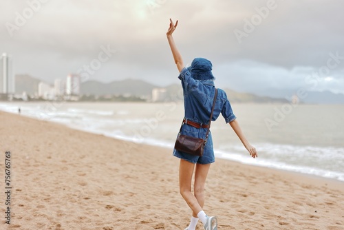 Serene Solitude: A Young, Attractive Caucasian Female Enjoying the Sunny Beach Vacation, Walking Alone along the Beautiful Coastline