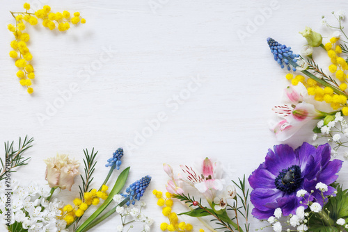 White wooden background with spring colorful bright flowers and copy space. Decorative floral card for holidays.