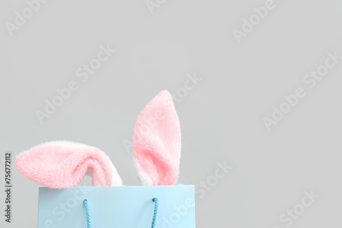 Shopping bag with fluffy Easter bunny ears on white background