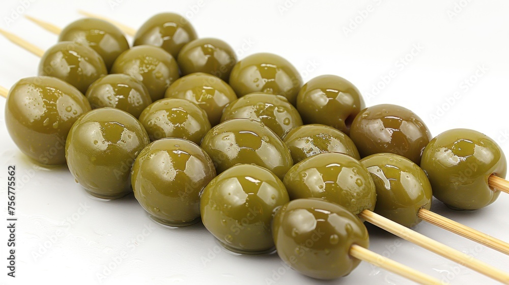 a pile of olives sitting on top of wooden skewers with toothpicks sticking out of them. a pile of olives sitting on top of wooden skewers with toothpicks sticking out of them.