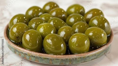 a bowl full of green olives sitting on a white tablecloth with a white tablecloth on the table. photo