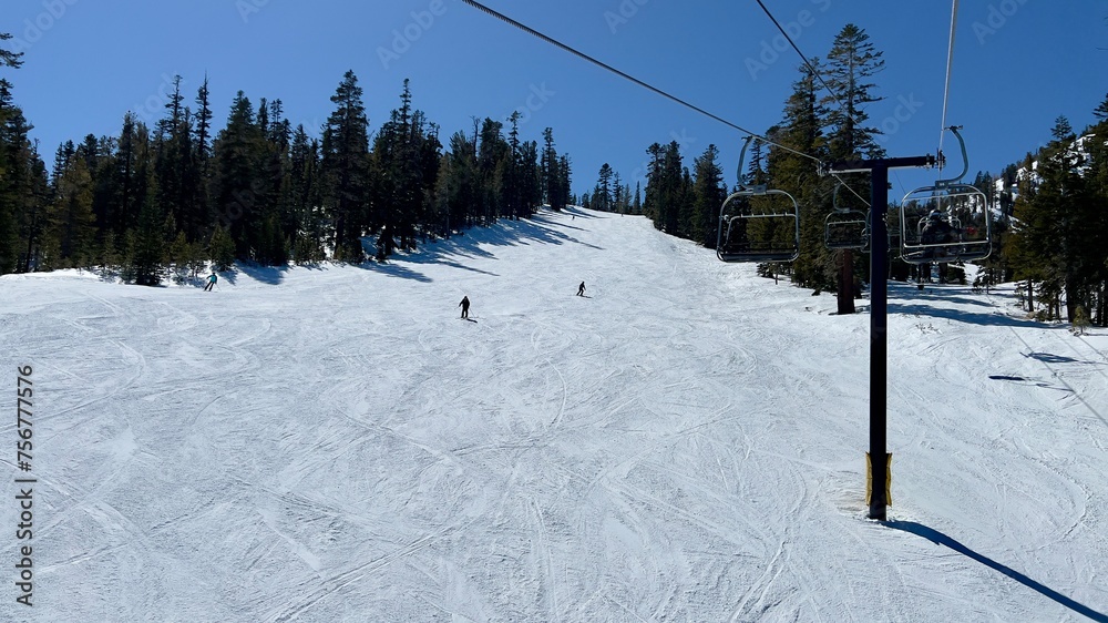 Looking across mountain slope with anonymous, silhouetted skiers descending, chair lift on the right. Mammoth Mountain, California Looking across mountain slope with anonymous, silhouetted skiers descending, chair lift on the right. Mammoth Mountain, California