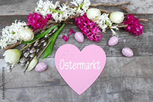 Der Text Ostermarkt auf ein Herz geschrieben mit Osterdekoration und Blumen. photo