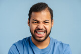 Expressive African American man with braces, grimacing with rage and looking at the camera