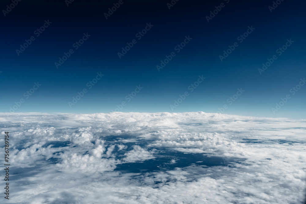 Naklejka premium Above the clouds, view out of plane window, blue sky