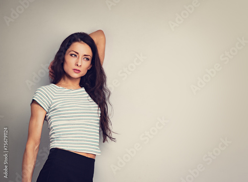 Beautiful young business woman thinking and looking up on blue studio background on empty copy space. Closeup